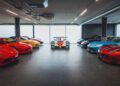 A race car is parked in the center of a showroom at an RM Sotheby’s Zurich auction, surrounded by multiple high-end sports cars and hypercars in red, yellow, blue, and black.