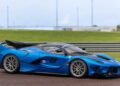 A blue Ferrari hypercar with the number 8 on the door drives on a racetrack, with grassy areas and barriers in the background—a striking sight reminiscent of top-tier lots at an RM Sotheby’s Zurich auction.