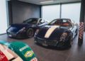 Two Ferrari 599 GTO hypercars—one in dark blue and one with white racing stripes—are parked indoors beside a partially visible green and white race car, evoking the spirit of an RM Sotheby’s Zurich auction.