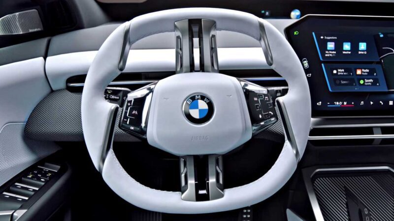 Close-up of a BMW car’s square-shaped steering wheel, digital instrument cluster, and infotainment screen—showcasing the innovation found as BMW iX3 launches the Neue Klasse era with a 400-mile range and 463 HP.