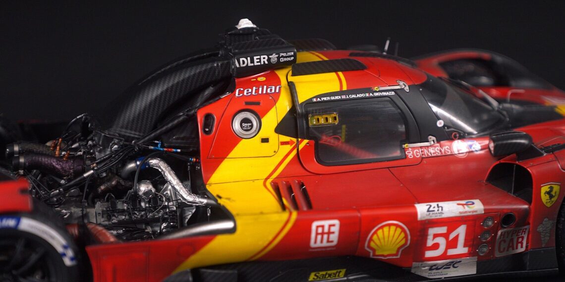 Close-up view of a red and yellow Ferrari race car from the Amalgam Collection, highlighting the cockpit, exposed engine components, and number 51 on the door.