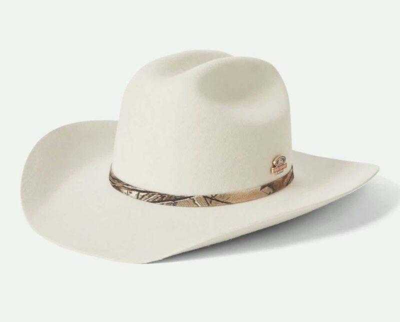A cream-colored cowboy hat with a wide brim and a patterned band around the crown, featuring a small metallic badge on the side. Part of the Brixton Limited Edition—buy this stylish accessory for your next Ford adventure.