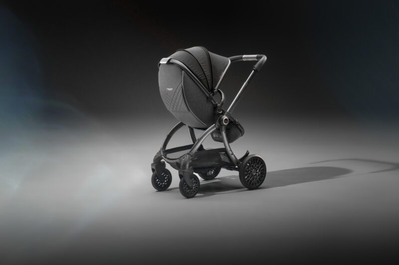 A modern black baby stroller with a rounded canopy, inspired by Aston Martin strollers—perfect for car lovers raising the next generation. Shown on a plain, dark background.