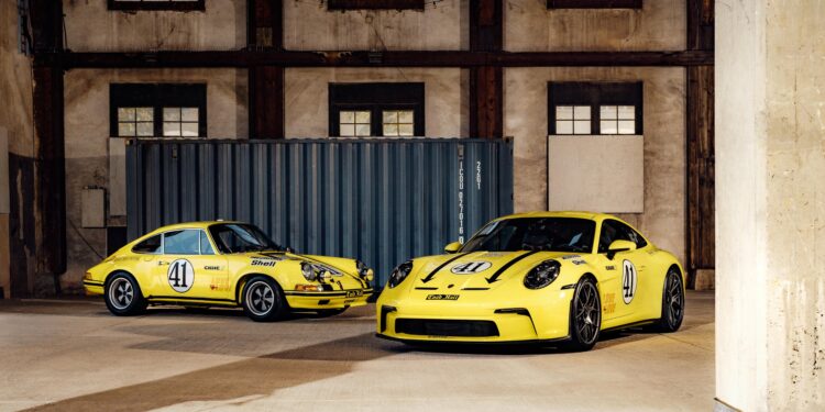 Two yellow Porsche 911 S/T sports cars, each bearing racing number 41 decals, are parked side by side in an industrial warehouse with exposed beams and a large shipping container—a true legend in the world of Porsche 911.