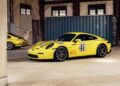 Two yellow Porsche 911 legends, both with racing decals like number 41 and "LOVE LIVE," are parked inside an industrial garage, set against the backdrop of a blue shipping container.