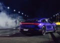 A blue Porsche Taycan Turbo GT with illuminated taillights is positioned on the Sydney Dragway at night, ready to chase a quarter-mile record as tire smoke billows and people watch in the background.