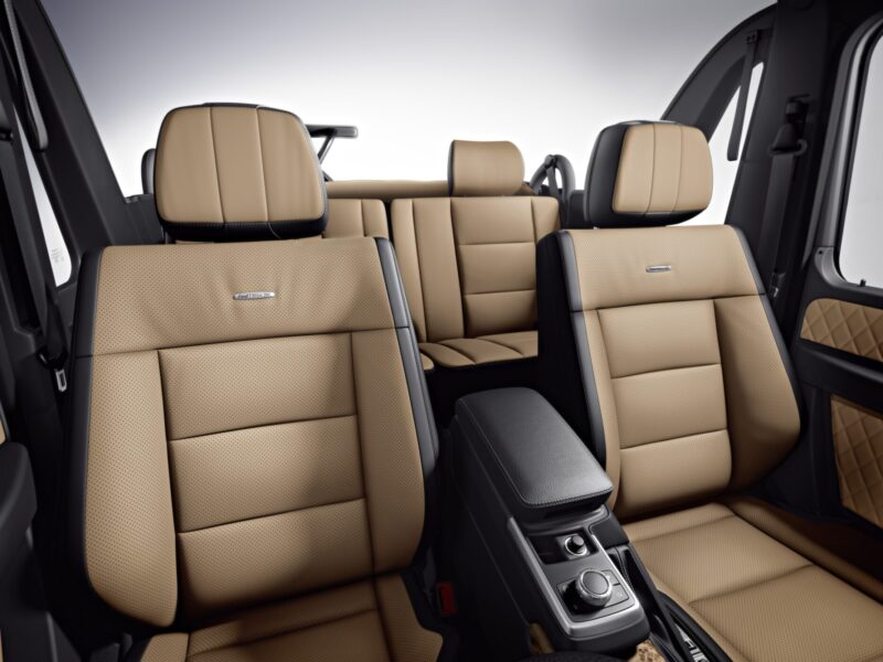 Interior view of a vehicle with tan leather seats, black trim, and a central control console. Two rows of seats are visible, reflecting the luxury seen in models like the Mercedes Teases G-Class Cabriolet Revival With Four Doors Instead of Two.
