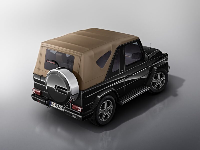 A black Mercedes-Benz G-Class convertible with a tan soft top is shown from the rear at a three-quarter angle in a studio setting, echoing the excitement as Mercedes teases a G-Class Cabriolet revival with four doors instead of two.