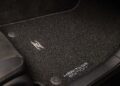 Close-up of a car's black floor mat with a metallic logo and "Heritage Edition" text embroidered near the corner, showcasing a 300ZX-Inspired Design for the Nissan Z Heritage Edition.