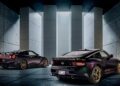 Two black 2026 Nissan Z sports cars with gold wheels are parked indoors in a modern, concrete-walled space, their look echoing the 300ZX-Inspired Design and illuminated by vertical light panels in the background.