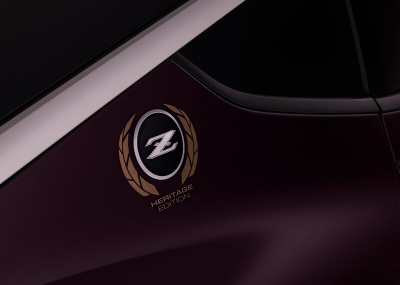 Close-up of a Nissan Z Heritage Edition emblem with gold laurel leaves, highlighting the 300ZX-inspired design on the side of a dark purple car.