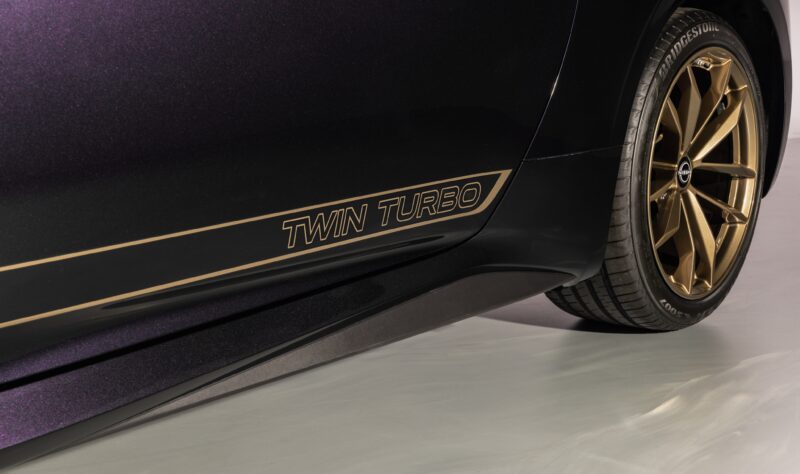 Close-up of a Nissan Z Heritage Edition's rear side panel, showcasing a "TWIN TURBO" decal and a bronze-colored wheel with Bridgestone tire branding—highlighting its 300ZX-Inspired Design.