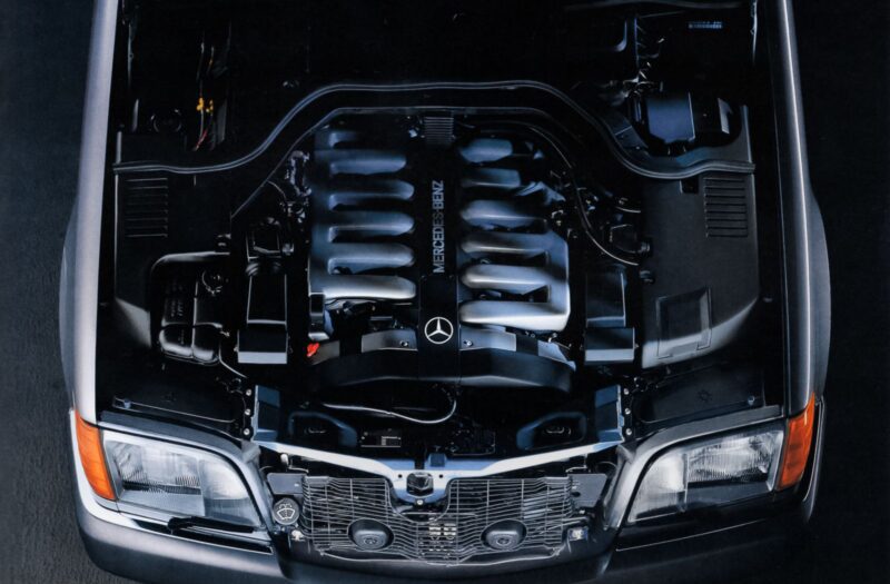 Overhead view of a car engine bay showcasing a prominently labeled Mercedes-Benz V12 engine inside a sleek black vehicle, capturing the innovation expected from 2030 models.