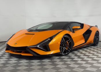 An Arancio Atlas Lamborghini Sián sports car is parked indoors on a patterned floor, viewed from the front left angle, and is now for sale.