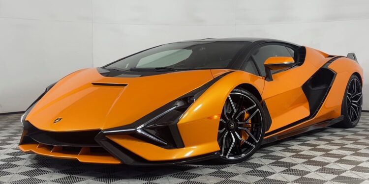 An Arancio Atlas Lamborghini Sián sports car is parked indoors on a patterned floor, viewed from the front left angle, and is now for sale.