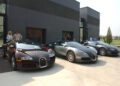Three legendary Bugatti Veyron cars, including the rare Chassis 5.0, are parked side by side outside a modern building, with several people standing nearby.