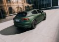 A matte green Maserati Grecale Folgore SUV, showcasing advanced EV Tech, is parked on a modern paved driveway beside a glass building, with its rear and left side visible.