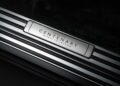 A close-up of a metal door sill plate engraved with "Phantom Centenary Private Collection" on a luxury car, celebrating how Rolls-Royce honors 100 years of Phantom with this groundbreaking private collection; dark trim and carpeting are visible.