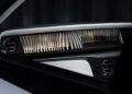 Close-up of a car interior, showing the dashboard with vertical metallic slats, round air vents, and a white panel—an exquisite touch as Rolls-Royce honors 100 years of Phantom with groundbreaking private collection details.