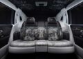 The rear seats of this luxury car feature elaborate black and white upholstery with intricate designs, ambient lighting, and a star-patterned ceiling, reflecting the opulence of the Rolls-Royce Honors 100 Years Of Phantom With Groundbreaking Private Collection.