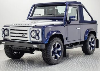 A unique creation: a blue and silver two-door SUV with off-road tires and a soft top roof, parked indoors on a checkered garage floor.