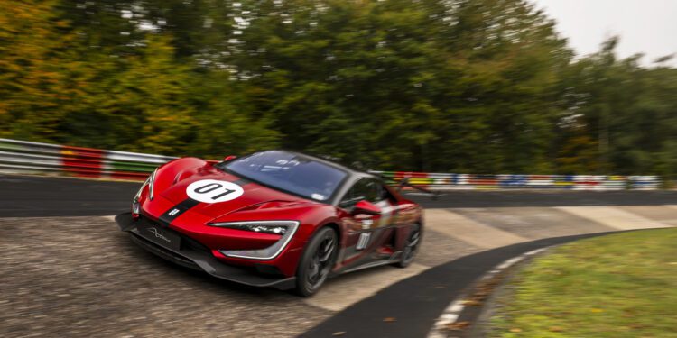 A red race car with the number 01, inspired by electric hypercars like the YANGWANG U9, drives quickly around a curve on a racetrack surrounded by trees.