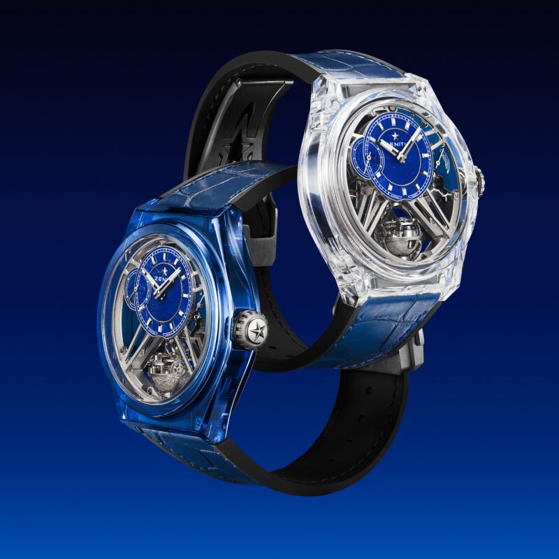 Two luxury Zenith wristwatches from the Sapphire Collection feature blue dials and exposed tourbillon mechanisms, with transparent and blue cases, elegantly displayed against a blue gradient background.