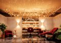 Luxurious salon interior at Aureum Estate, Dubai Hills, featuring a central styling chair, red seating, illuminated shelves with products, decorative ceiling lights, and lush green plants on a polished marble floor.