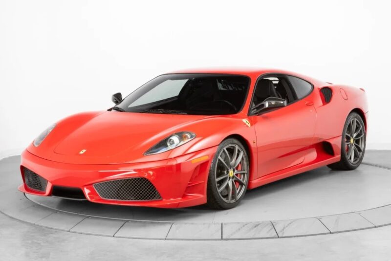 A red Ferrari 430 Scuderia sports car is parked in a white studio setting, viewed from the front left angle, showcasing the iconic Prancing Horse.