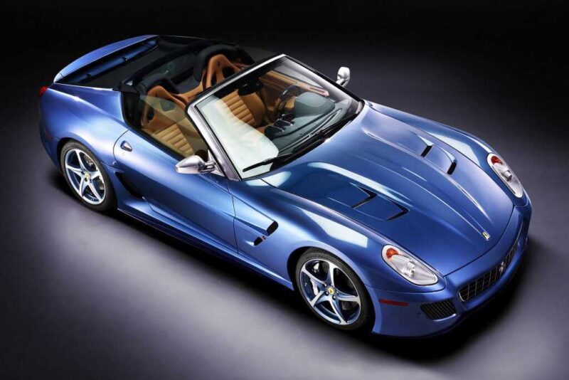 A blue convertible sports car with tan leather interior, viewed from above on a dark background—reminiscent of the exclusivity found in 1-of-1: Rarest Ferraris In The World.