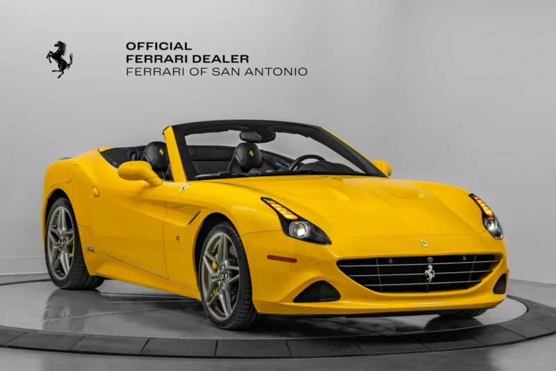 A yellow Ferrari convertible, showcasing one of the iconic Ferrari colors, is displayed in a showroom with "Official Ferrari Dealer Ferrari of San Antonio" signage on the wall.