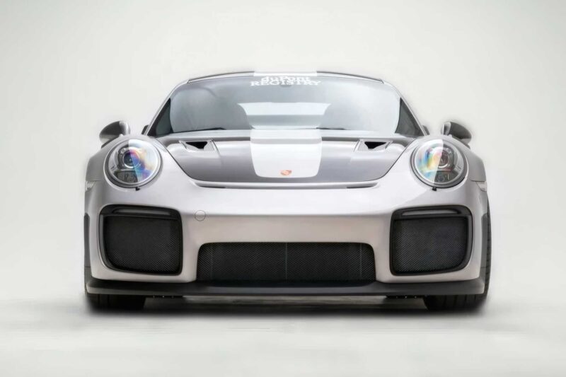Front view of a silver 2018 Porsche 911 GT2 RS, the last of its kind before electrification, with prominent headlights, large air intakes, and a white racing stripe on the hood against a plain background. For sale now.