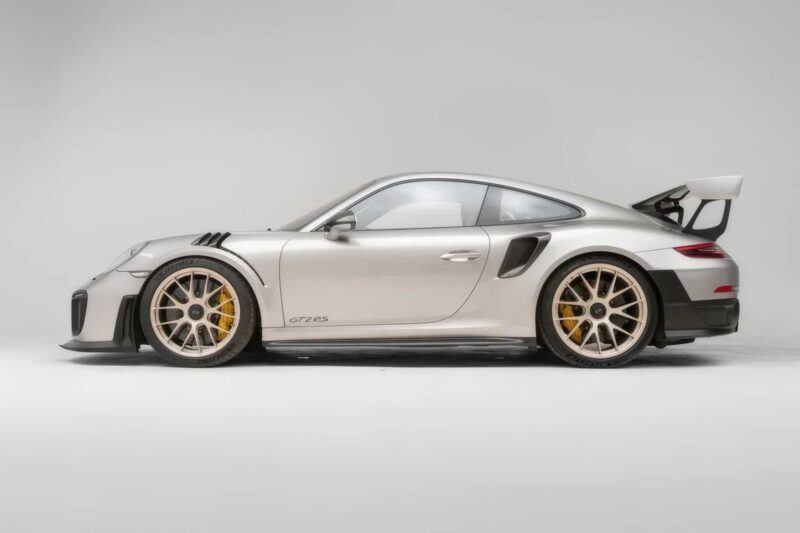 Side view of a silver 2018 Porsche 911 GT2 RS, last of its kind before electrification, with large rear wing and yellow brake calipers, photographed against a plain light background. For sale now.