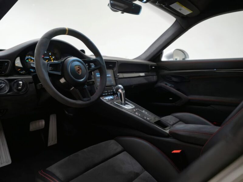 For Sale: 2018 Porsche 911 GT2 RS—last of its kind before electrification. The interior features a black leather steering wheel, digital dashboard, gear shift, and black seats with red stitching.