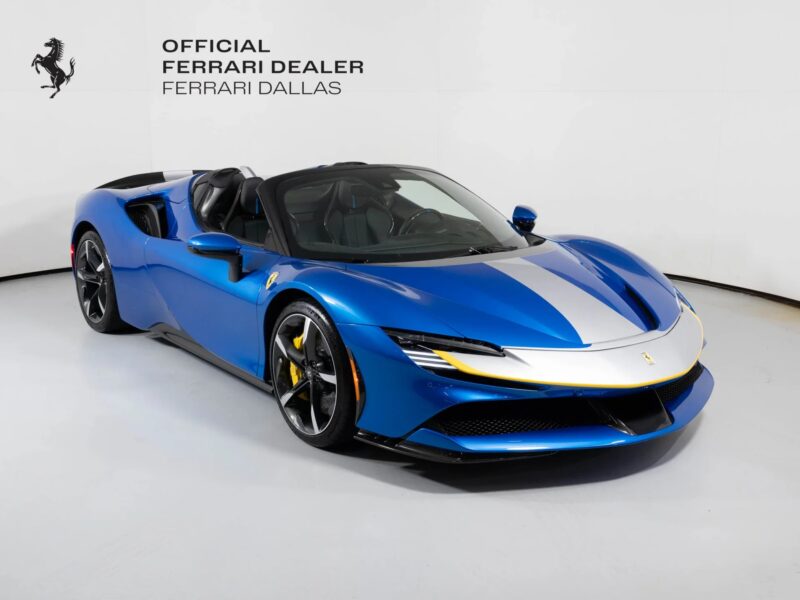 A blue Ferrari convertible with a white racing stripe, showcasing unique Ferrari colors, is displayed in a showroom labeled "Official Ferrari Dealer Ferrari Dallas.