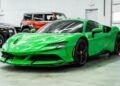 A bright green Ferrari with black wheels is parked indoors on a concrete floor near other vehicles, showcasing one of the bold Ferrari colors.