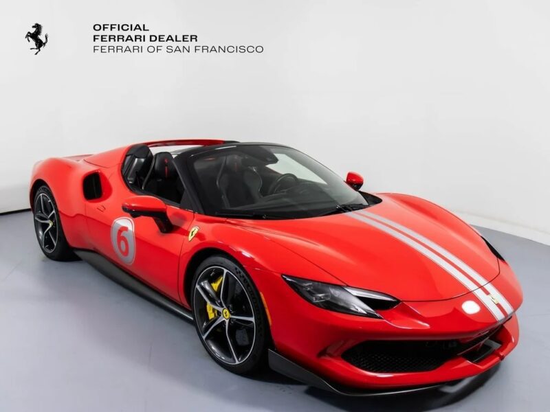 A red Ferrari sports car with white racing stripes and the number 6 on the side, this exotic car is displayed in a showroom with “Ferrari of San Francisco” signage in the background.