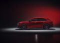 Side view of a red SUV parked on a light gray platform against a dark background with red lighting, highlighting the bold design in this Review: 2025 Audi RS Q8 Performance.