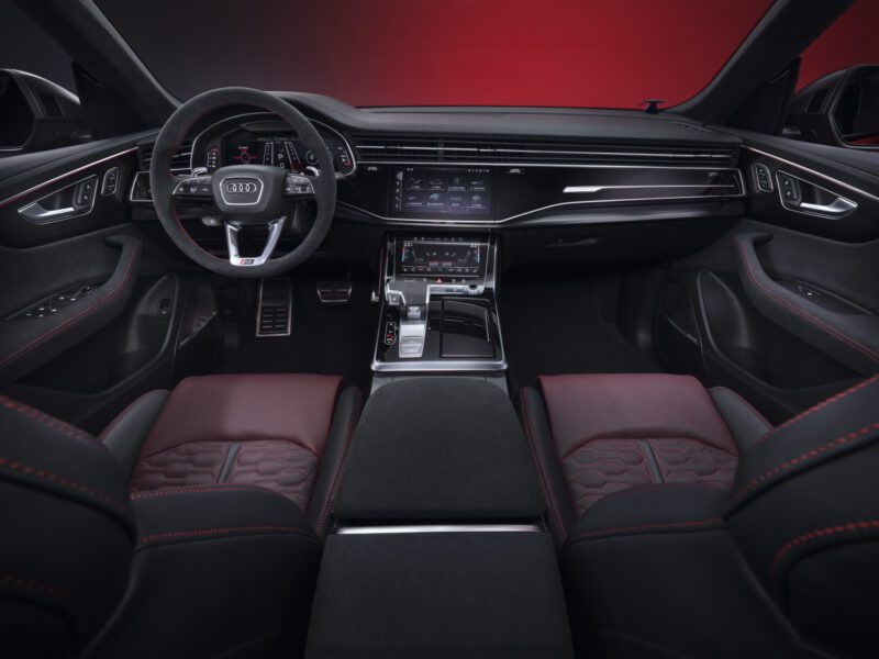 Review: 2025 Audi RS Q8 Performance interior with black and red leather seats, digital dashboard, touchscreen center console, and multi-function steering wheel, photographed from the back seat.
