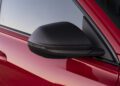 Close-up of a carbon fiber side mirror on a red car, with the window and part of the door visible in the background, as seen in our Review: 2025 Audi RS Q8 Performance.