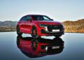 Review: 2025 Audi RS Q8 Performance—A striking red SUV parked on a reflective surface, set against a hilly landscape and clear sky.