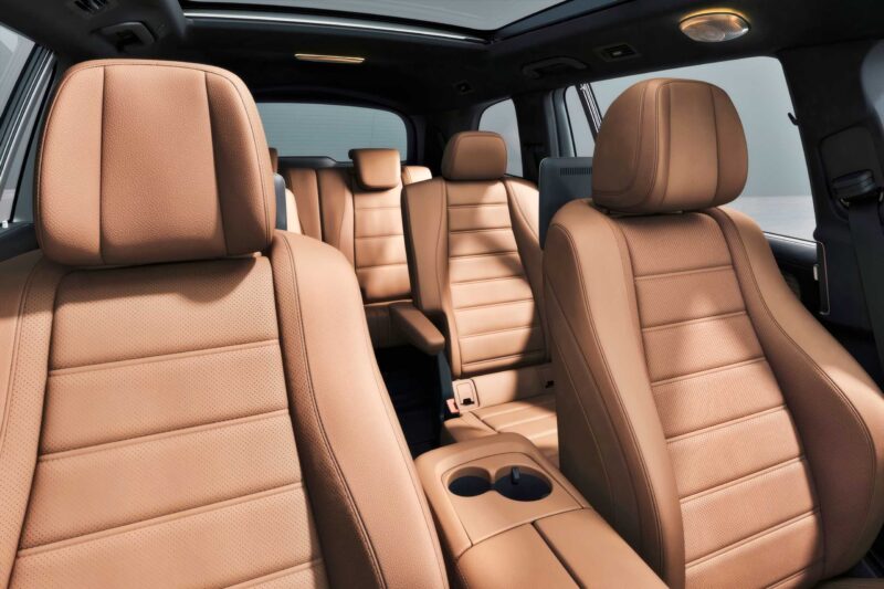 Interior view of the Review: 2025 Mercedes-Benz GLS 580 4Matic, featuring three rows of tan leather seats, a center console with cup holders, and a sunroof.