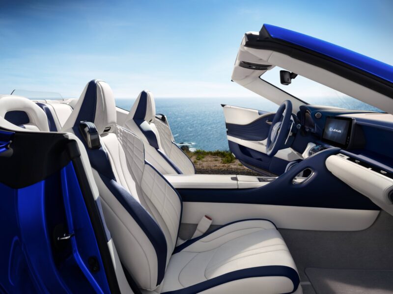 Review: 2025 Lexus LC 500 Convertible with a stunning white and blue leather interior, parked by the ocean on a sunny day, top down and the sparkling sea as a breathtaking backdrop.