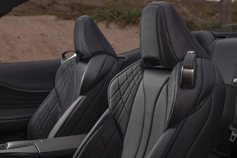 Review: 2025 Lexus LC 500 Convertible—Black leather front seats showcase stitched diamond patterns and headrests, set against a blurred outdoor backdrop for a luxurious driving experience.