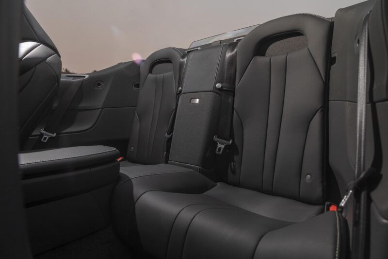 Rear seats of the 2025 Lexus LC 500 Convertible feature black leather upholstery, headrests, seatbelts, and a center fold-down armrest. Review: 2025 Lexus LC 500 Convertible highlights luxury and comfort in every detail.