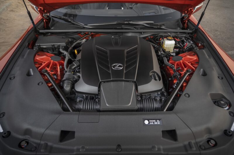 Close-up view of a Lexus car engine bay with the hood open, showcasing the engine and various mechanical components in the Review: 2025 Lexus LC 500 Convertible.