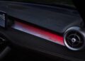 The image shows an updated car dashboard with a digital display, circular air vent, illuminated red honeycomb pattern, and the word "Tonale" inscribed on the trim—highlighting the refined interior of the 2026 Alfa Romeo Tonale.