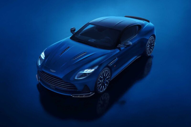 An Aston Martin DB12 S blue sports car photographed from above on a glossy blue surface under studio lighting, capturing the essence of Super Tourers.