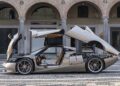 A silver Speedster with its doors, trunk, and hood open is parked on a cobblestone street in front of an arched building, reminiscent of the exclusivity showcased at the Las Vegas Concours.