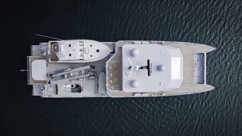 Aerial view of THE BEAST, an IKONIK Yachts power catamaran, gliding on calm blue water with its spacious deck, modern equipment, and inviting seating areas.